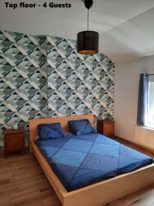 a bedroom with a blue bed with a geometric wall at Relax Sax Appartment in Dinant