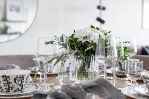 a table with glasses and a vase with white flowers at Nordic city apartment by R&K Apartments in Rovaniemi