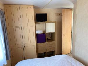 a bedroom with a bed and a cabinet and a television at Golden Sands 6 Berth Beach front Ingoldmells beds made up for arrival WIFI in Ingoldmells +42 photos