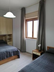 1 dormitorio con 2 camas y ventana en sant'orsola holiday home, en Misterbianco