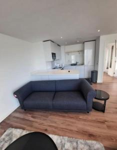 a blue couch in a living room with a kitchen at Luxurious 3 Bedroom Flat Close To East Croydon Station - Gym - Sleeps 6 in London