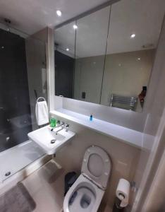 a bathroom with a sink and a toilet and a mirror at Luxurious 3 Bedroom Flat Close To East Croydon Station - Gym - Sleeps 6 in London