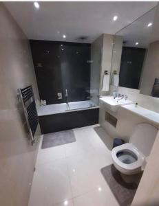 uma casa de banho com uma banheira, um WC e um lavatório. em Luxurious 3 Bedroom Flat Close To East Croydon Station - Gym - Sleeps 6 em Londres