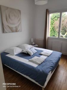 uma cama com lençóis e almofadas azuis num quarto em Maison 8 P. Bien situé. Entrée et sortie facile. em Ruelle-sur-Touvre