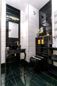 a bathroom with a black toilet and a sink at Apartament Versace Księcia Witolda in Wrocław