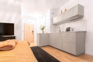 a kitchen with white cabinets and a bed in a room at Apartament Versace Księcia Witolda in Wrocław