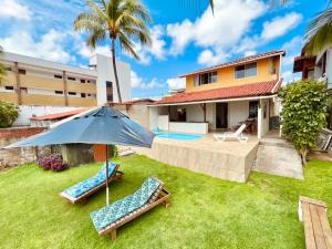 a backyard with two lawn chairs and an umbrella at Casa Pé na Areia in Pirangi do Norte