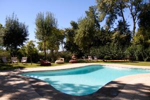 una piscina en un patio con sillas y árboles en Monte dos Pensamentos - Turismo Rural, en Estremoz