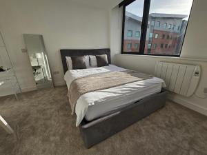 a bedroom with a large bed with a large window at Brand New Trafford Apartment in Manchester