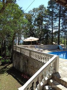 a fence with an umbrella next to a swimming pool at Casa de Campo em Serra da Cantareira in Mairiporã