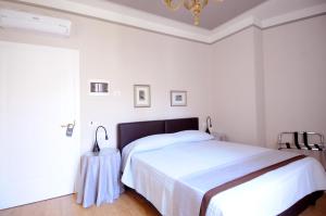 a white bedroom with a bed and a chandelier at B&B Cangrande di Danese-Viviani in Verona