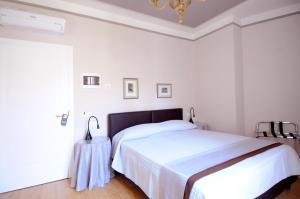 ein weißes Schlafzimmer mit einem Bett und einem Kronleuchter in der Unterkunft B&B Cangrande di Danese-Viviani in Verona