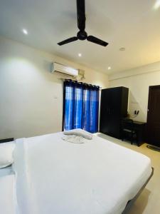 a bedroom with a white bed with a ceiling fan at Tulips Residency - Airport in Pīlamedu