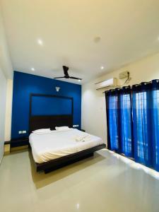um quarto com uma cama com uma parede azul em Tulips Residency - Airport em Pīlamedu
