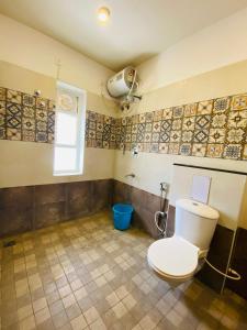 a bathroom with a toilet and a blue bucket at Tulips Residency - Airport in Pīlamedu