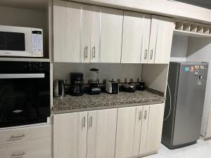 a kitchen with white cabinets and a microwave and a refrigerator at Casa independiente, ciudad jardín in Cali