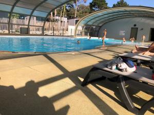 een persoon op een bankje naast een zwembad bij Cottage Jullouville récent l'Edune résidence vacances - plage 150 m -piscine in Jullouville-les-Pins