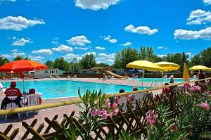 a pool with people sitting in chairs under umbrellas at Campeggio del Garda in Peschiera del Garda