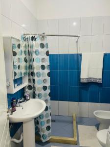 een blauwe en witte badkamer met een wastafel en een douche bij Dardana&Gerjon apartament in Bathoria