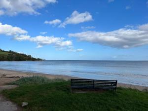 a bench sitting on the beach near the water at The Mended Drum in Fortrose