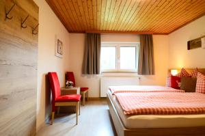 a bedroom with a bed and a red chair at Lammerauhof in Abtenau