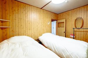 HDO Furano Garden House في فورانو: سريرين في غرفة بجدران خشبية