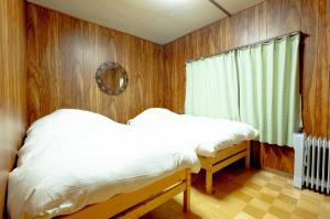 a bedroom with wooden walls and two beds and a window at HDO Furano Garden House in Furano