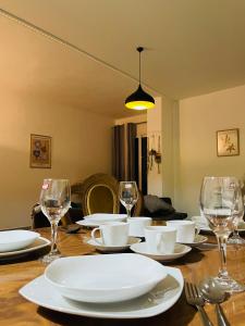 een tafel met witte borden en wijnglazen erop bij Dardana&Gerjon apartament in Bathoria