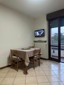 comedor con mesa, sillas y TV en Bilocale condominio Trifoglio, en Gallarate