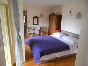 a bedroom with a bed with a purple comforter at Guesthouse Kuća na šterne in Lovran