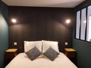 a bedroom with a large bed with two pillows at L'atelier, appart avec jardin à 100 m de la mer. in Donville-les-Bains