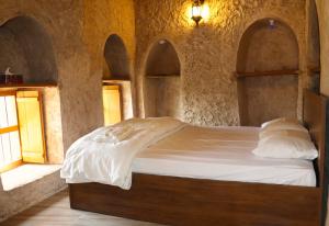 a bedroom with a bed in a stone wall at Misfah Old House in Misfāh