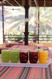 a tray of different colored glasses on a table at Misfah Old House in Misfāh