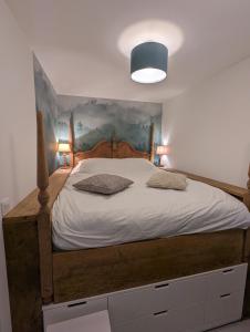 1 dormitorio con 1 cama grande de madera y 2 almohadas en Gîte des Genêts en terrasses, en Bièvre