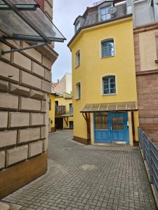 a yellow building with a blue door on a street at B&R Ganze Apartment Süd Nürnberg in Nürnberg