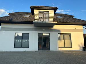 a white house with a balcony on top of it at Apartament Oksford 1 in Okszów