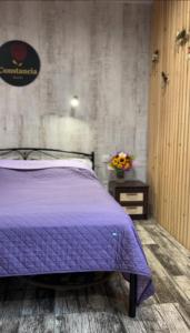 ein Schlafzimmer mit einem lila Bett und einem Tisch mit Blumen in der Unterkunft Constancia in Kamjanez-Podilskyj