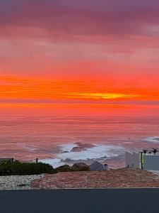 una puesta de sol sobre el océano con un cielo rojo y naranja en Versveld 35, en Yzerfontein