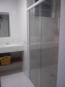 La salle de bains est pourvue d'une douche en verre et d'un lavabo. dans l'établissement Privilégio em Cabo Frio, à Cabo Frio