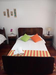 Una cama con almohadas coloridas y un ordenador portátil. en Casa do Brasão en Lajes do Pico