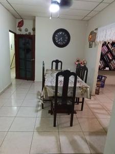 uma sala de jantar com mesa e cadeiras e um relógio na parede em Casa en Las Tablas em Las Tablas