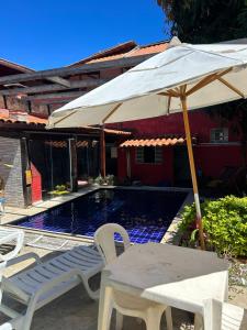 a table and chairs with an umbrella next to a pool at Pousada Núcleo da Serra in Serra do Cipo
