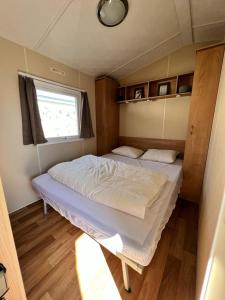 a twin bed in a small room with a window at Stacaravan Middelkerke in Middelkerke