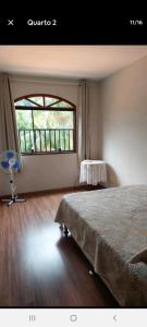 1 dormitorio con cama y ventana grande en Aconchego no bairro mais charmoso da serra., en Nova Friburgo