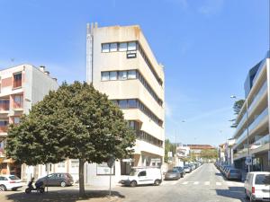 a tree in front of a building on a street at Mercadoflat in Póvoa de Varzim