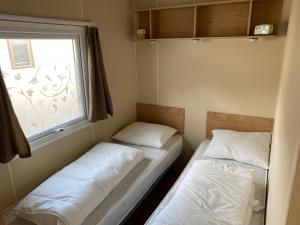 2 łóżka w małym pokoju z oknem w obiekcie Stacaravan Middelkerke w mieście Middelkerke