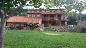 una casa grande con una pared de piedra en un patio en Casa Rural La Tablilla y La Terraza, en Navalperal de Tormes