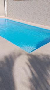 einem Pool mit blauem Wasser und einem Schatten für Personen in der Unterkunft Lar de PAZ in São Pedro da Aldeia