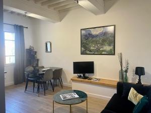 ein Wohnzimmer mit einem Sofa und einem Tisch mit einem TV in der Unterkunft Appartement rénové de caractère/ parking privé in Saint-Rémy-de-Provence