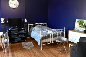 1 dormitorio azul con 1 cama y TV en La Domus Lemaitre 5- Parking - TV - Wifi 